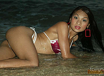 Sultry asian model poses in the ocean water at sunset